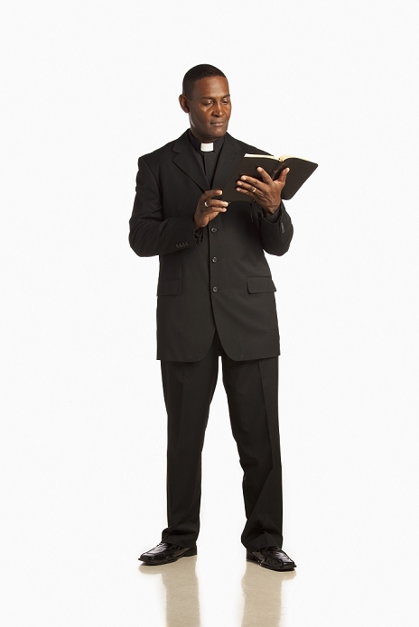 A Man Wearing A Clerical Collar And Reading From The Bible