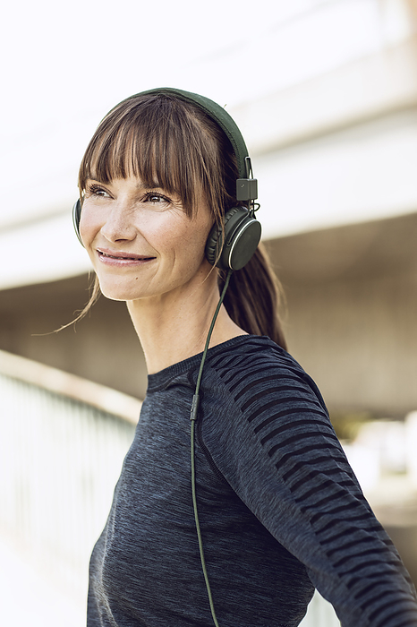 A woman listening to music Sportive woman with headphones, doing her fitness training outdoors