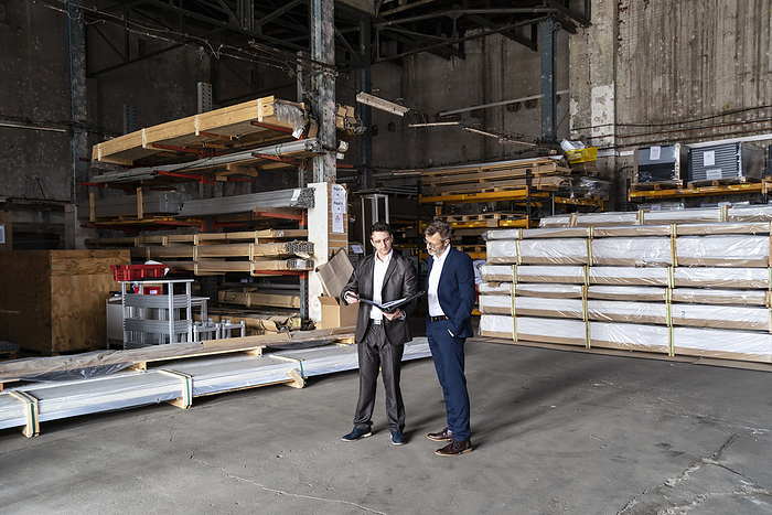 Two businessmen with folder talking in an old storehouse