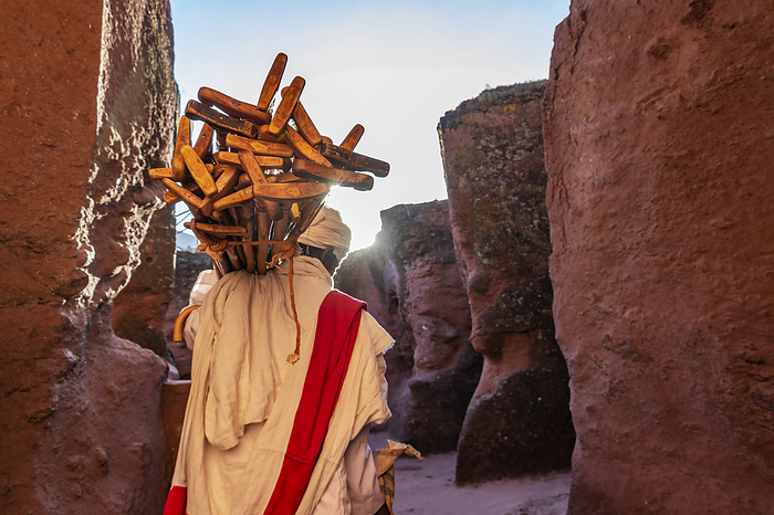 Ethiopian Orthodox priest carrying prayer sticks by Biete Qeddus Mercoreus (House of Saint Mercurius or House of Mark the Evangelist) Ethiopian Orthodox rock-cut church in the Southern Group of the Rock-Hewn Churches; Lalibela, Amhara Region, Ethiopia, Photo by Peter Langer