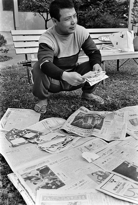 1964 Tokyo Olympics One day after winning Japan s first gold medal, weightlifting featherweight Yoshinobu Miyake checks out the newspapers reporting his accomplishment and congratulatory telegrams on the lawn in front of the athletes  village dormitory.