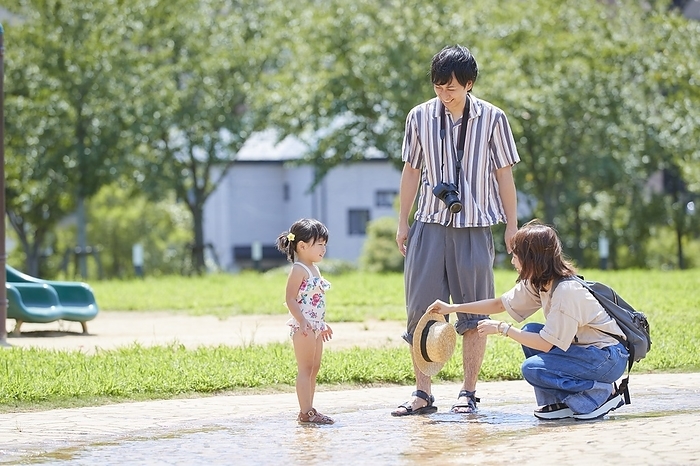 A Japanese family of three playing in the park.