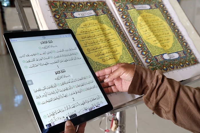 Masjid Nurul Naim mosque. Book with the first page of the Quran and Imam reading a digital Quran on a tablet.  Phnom Penh. Cambodia. 