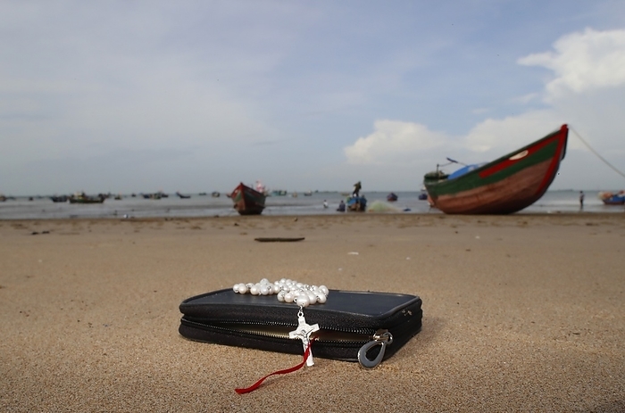 Catholic bible with a rosary on the beach.  Vung Tau. Vietnam. 