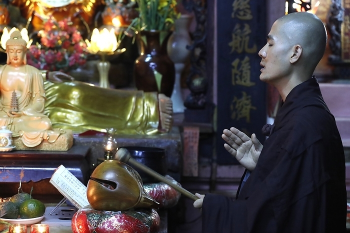 Buddhist ceremony at temple. Monk playing on a wooden fish (percussion instrument). Taoist temple. Emperor Jade pagoda (Chua Phuoc Hai).   Ho Chi Minh city. Vietnam. 