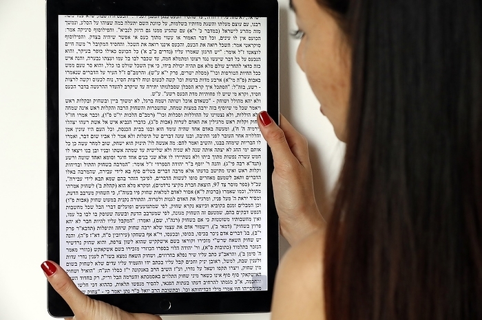 Jewish woman reading a digital Torah on tablet. 