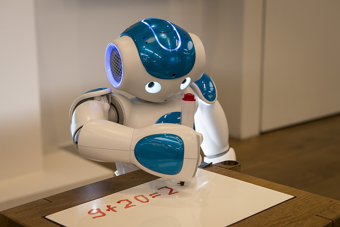 Nao robot writing Editorial use only   Nao robot writing an addition sum. Nao is an autonomous, programmable humanoid robot built by French company Aldebaran Robotics  now SoftBank Robotics . Its development began in 2004 and Nao robots have been used for research purposes, and as interactive and educational assistants for children in hospital and elderly people in care homes. Nao is 58 centimetres tall and weighs 4.3 kilograms. It is able to walk, run and even dance. On board cameras and sensors allow it to respond to visual and audible cues.