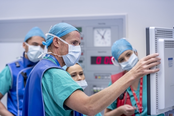 Spinal surgeons conferring during an operation MODEL RELEASED. Spinal surgeons conferring during an operation. Spinal surgery typically involves the use of bone grafts, bone cement and screws and plates to fix spinal injuries or other disorders.