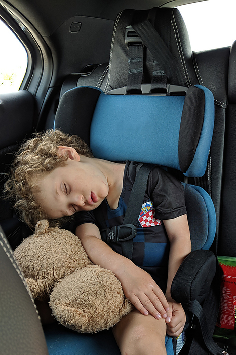 Little boy asleep in his car seat with his favorite stuffed toy