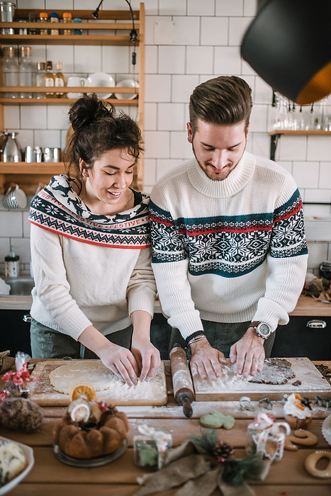 Friends in Christmas sweater make dough in the kitchen.