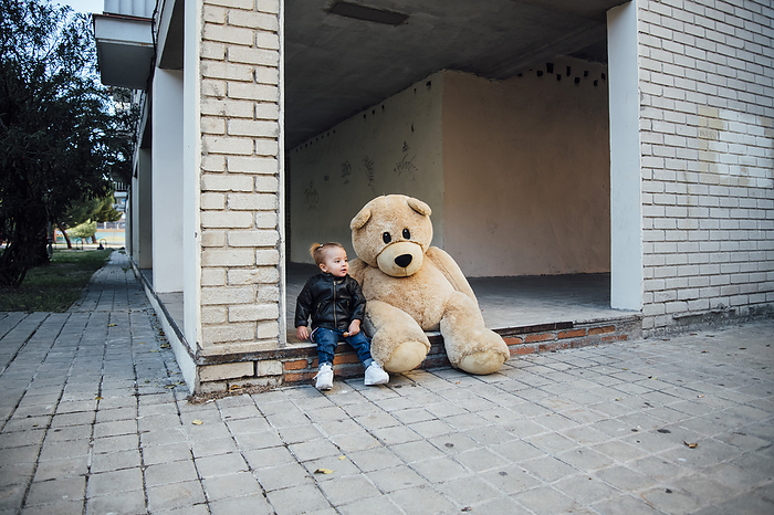 A little boy playing with a giant teddy bear.