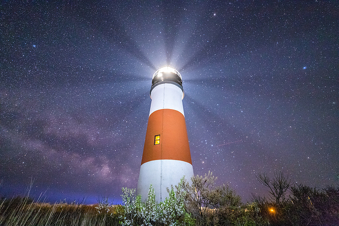 Lighthouse beaming in the night sky and Milky Way stars on Nantucket.
