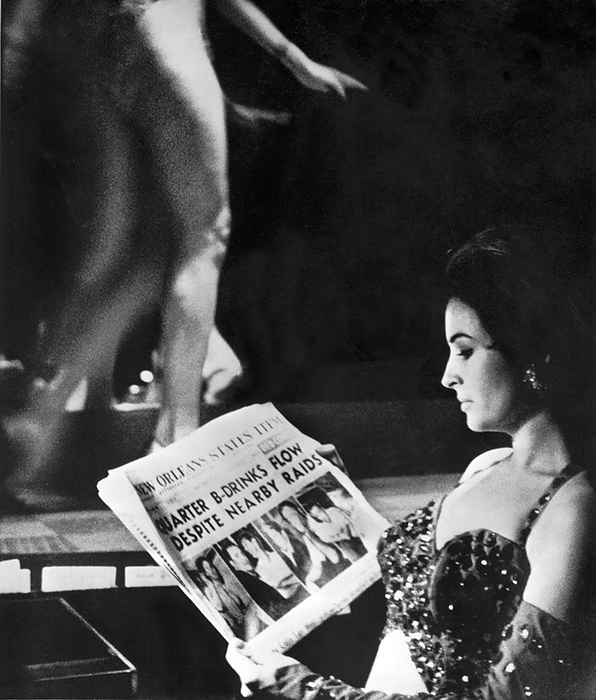 New Orleans, Louisiana:    August 11, 1962
An exotic dancer at the Gunga Den appears unconcerned about the vice raid headlines in the French Quarter in New Orleans.