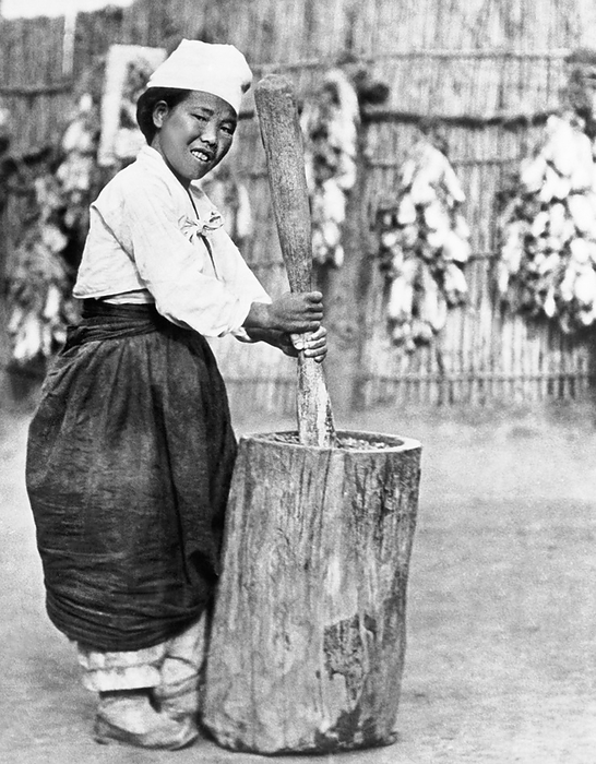Korea:  c. 1940
A Korean girl is mashing cooked soybeans with a wooden mortar and pestle which after fermenting for a few months will become miso.