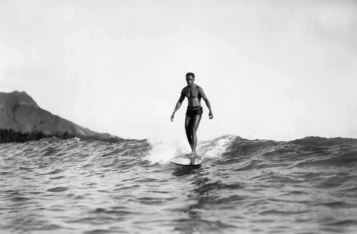 Honolulu, Hawaii:  1929
A man ridng on a surfboard at Waikiki Beach with Diamond Head in the background. He is possibly Duke Kahanamoku.
