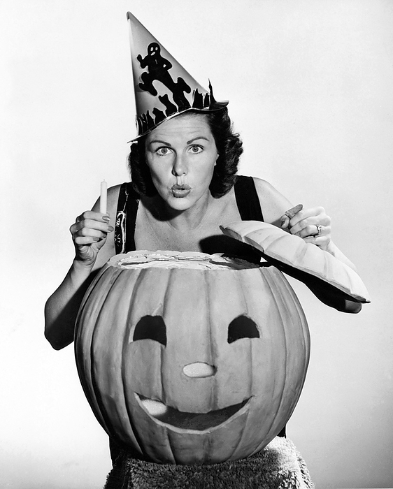 United States:  c. 1940
A woman looking scary with a pumpkin and a candle on Halloween.