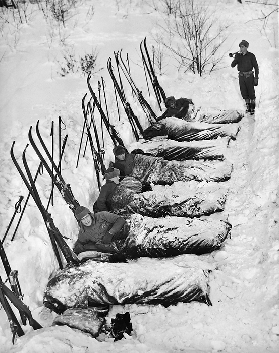 Pine Camp, New York:  January 27, 1940
U.S. Army ski Infantrymen on winter maneuvers being aroused from their sleeping bags in the outdoors by reivelle from the bugler.