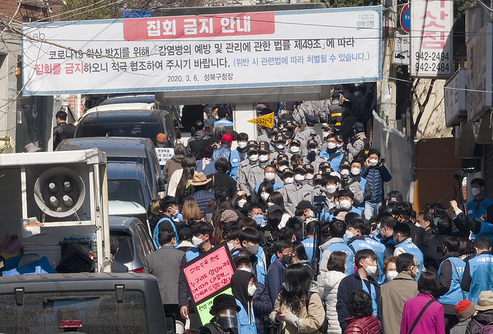 Daily life amid the spread of novel coronavirus in South Korea The Sarang Jeil Church, Mar 29, 2020 : Policemen  in gray uniform  stand as followers  in blue vest  at the Sarang Jeil Church, led by now jailed conservative pastor Rev. Jun Kwang Hoon, argue with the police and lead other churchgoers to the church, outside of the church in a housing redevelopment area in Seoul, South Korea. The church pressed ahead with Sunday religious services without abiding by some of the government s guidelines for preventing the massive spread of the novel coronavirus, which include keeping the distance between followers at least 2 meters while attending services and having their temperature checked. The Seoul City authorities on Mar 23 imposed a two week administrative order on the church, banning it from holding services until April 5.  Photo by Lee Jae Won AFLO   SOUTH KOREA 