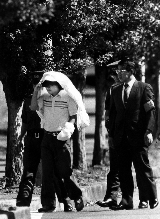 Serial Kidnapping and Murder of Young Girls  Konno Mari Case: Suspect Tsutomu Miyazaki, Kasuga machi, Iruma City, Japan, attends the kidnapping site inspection. Between 1988 and 1989, four young girls were lured and murdered one after another in Tokyo and Saitama  on July 23, 1989, Tsutomu Miyazaki, 26, a printing industry assistant in Itsukaichi, Tokyo, was arrested for kidnapping and indecent assault. Wearing a white safari jacket over his head, he was arrested in Iruma Village.