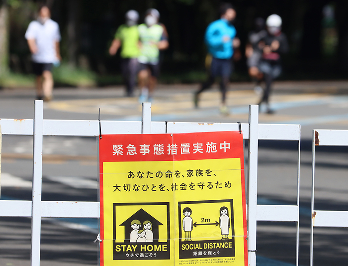 Park officials hold a banner to keep social distance for joggers at a park May 17, 2020, Tokyo, Japan   Joggers train at a park while a notice of  Stay Home  and to keep  Social Distance  is displayed in Tokyo on Sunday, May 17, 2020. Japanese government extended a state of emergency for Tokyo Metropolitan area on May 14.     Photo by Yoshio Tsunoda AFLO 