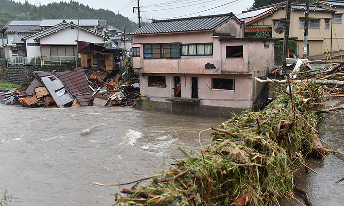 Debris over the parapet of a bridge. In the background are houses that were swept away by the river and destroyed. Debris over the parapet of a bridge. In the background is a broken house that was swept away by the river. 11 minutes, photo by Kimiya Tanabe