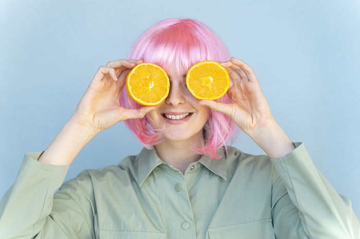 Barcelona, Spain, Young woman wearing pastel pop colorful funky look. Wig, pink, blue, pop, minimal, coloful, pastel, fun, funny, unique, different, colors, creative, pop, hairstyle, look, fashion Young woman wearing pink wig covering her eyes with oranges