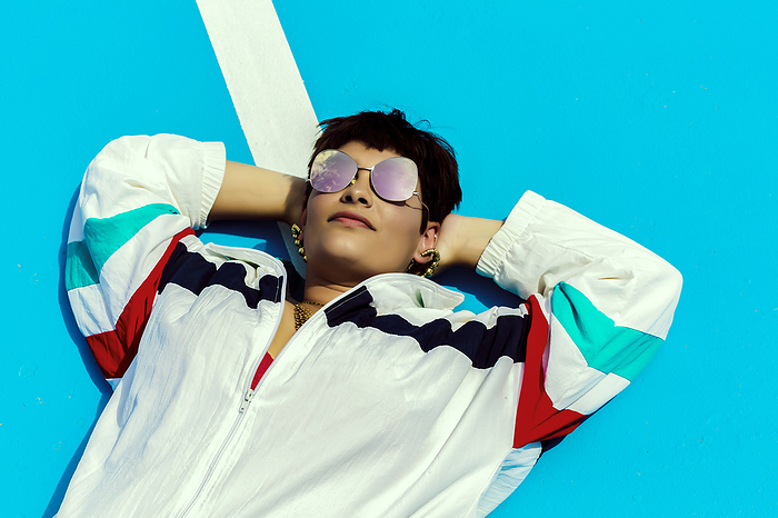 Portrait of woman wearing sunglasses and lying on ground