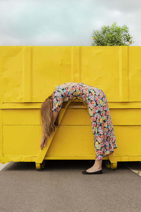 Woman in flower dress bending over attachment of yellow container