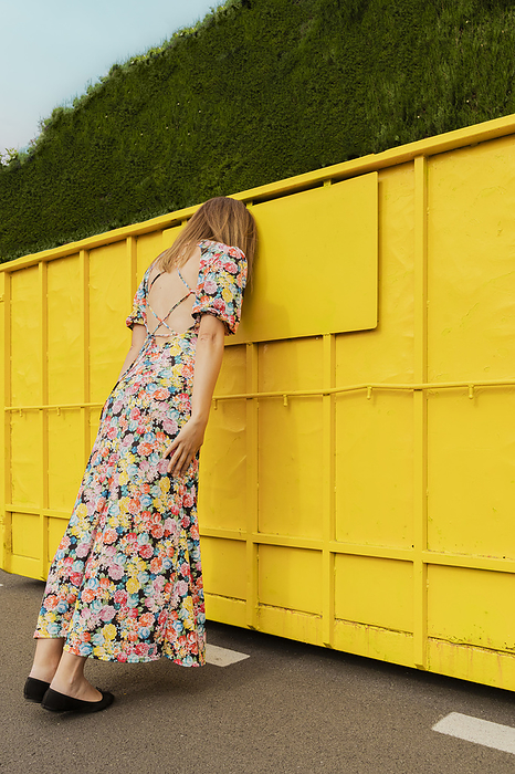 Desperate woman leaning head on yellow container in the street