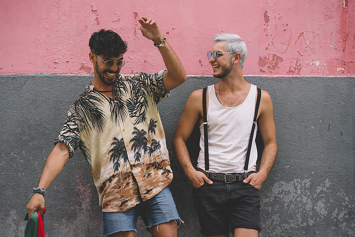 Gay couple in front of pink and grey wall