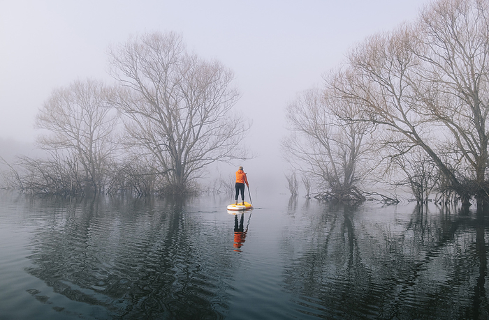 Woman stand up paddle surfing on a lake in the fog