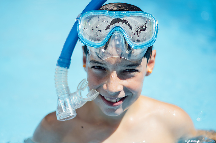 boy Portrait of smiling boy with diving goggles in pool
