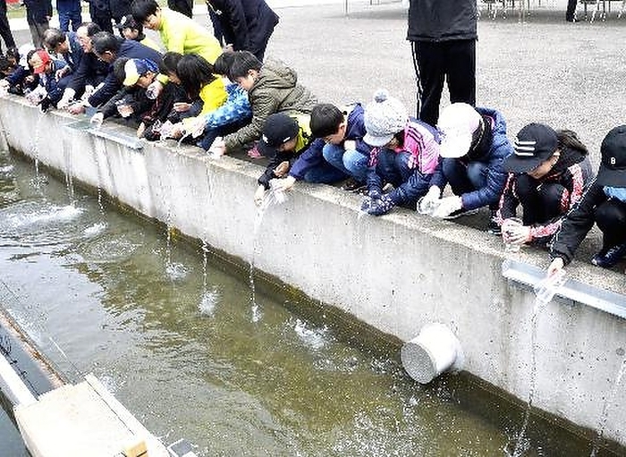 Release of juvenile salmon fry  Yoko , Tsuneo Children release fry into the sea at 10:30 a.m. on October 10 in Tokoro cho, Kitami City, hoping that they will come back safely.