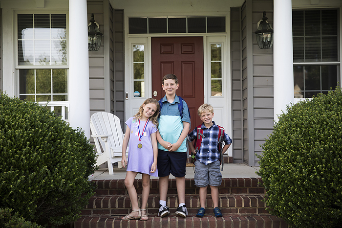 Three Smiling Happy Siblings With Backpacks Stand on Brick Front Steps, Easton, MD, United States