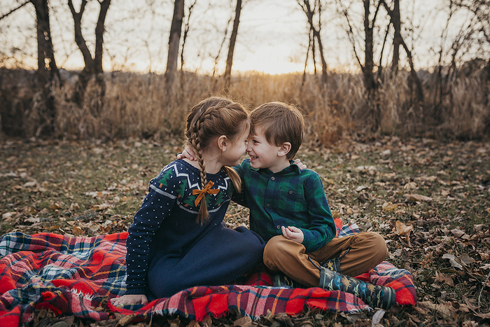 Boy and Girl Siblings smiling at each other sitting on red plaid blank, Milwaukee, WI, United States