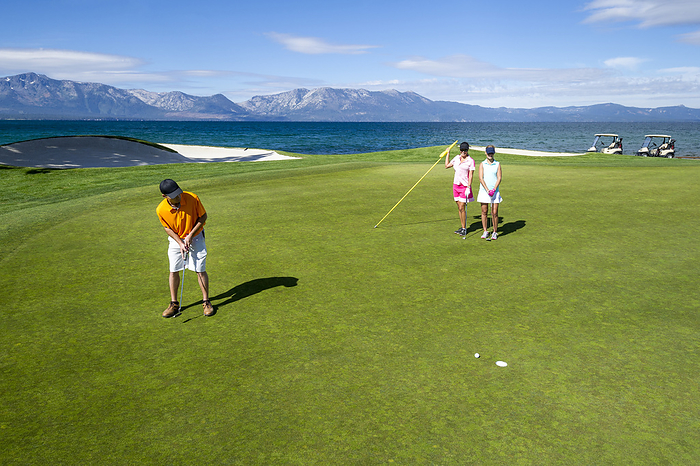 Three people playing golf at Edgewood Tahoe in Stateline, Nevada., United States, Nevada, Stateline