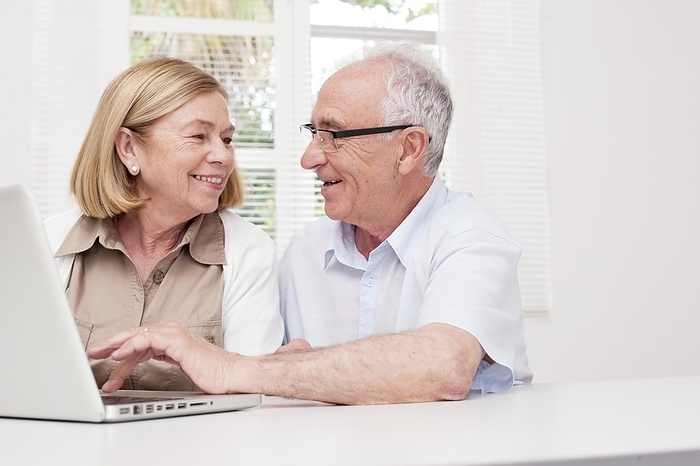 Senior couple using laptop Senior couple using laptop, smiling.