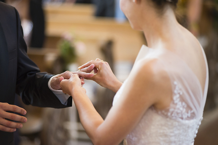 Bride wearing wedding ring to bridegroom while standing in church