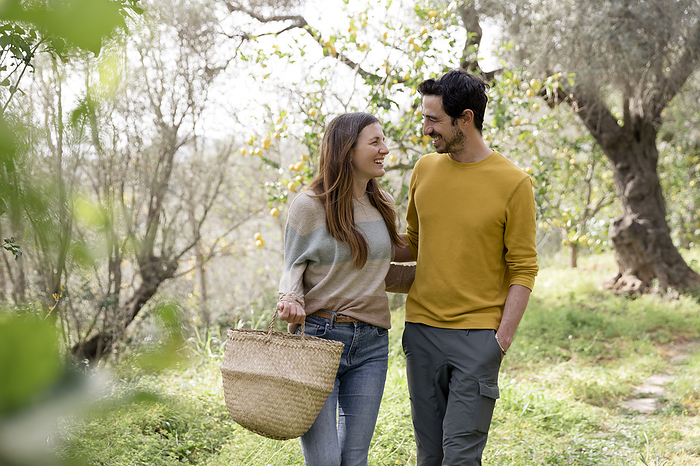 Romantic couple looking at each other while walking against trees in farm