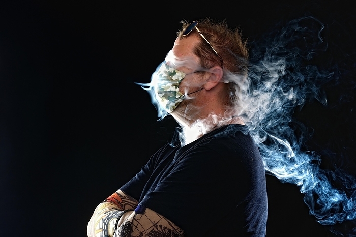 Man with face mask smoking cigarette, Corona series, Germany, Europe