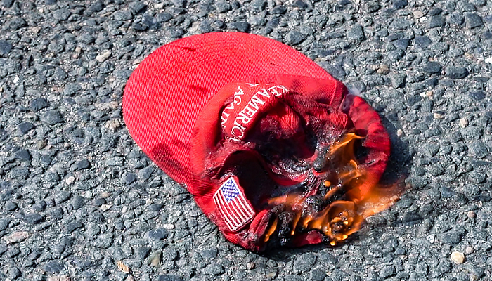 Anti Trump counter protest in Boston October 18, 2020, Copley Square, Boston, Massachusetts, USA: A counter demonstrator burns a MAGA hat during a rally in support of U.S. President Donald Trump sponsored by Super Happy Fun America, in Boston.  Photo by Keiko Hiromi AFLO  