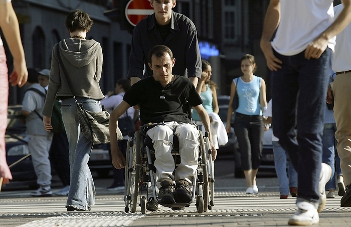 Wheelchair user Wheelchair user being pushed along a street.