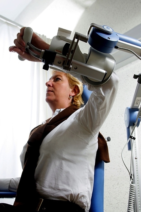 Physical therapy machine Physical therapy machine. Female patient with her arm in a motorised motion device used for continuous passive manipulation of the shoulder joint as part of a rehabilitation program. Photographed in Namur, Belgium, in 2004.