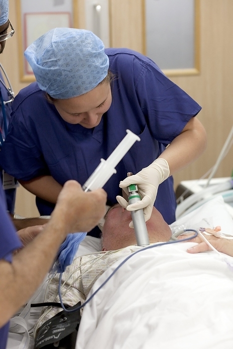 Intubating a patient Intubating a patient. Doctor inserting a breathing tube into a patient s throat prior to surgery. The tube is connected to a machine that will supply air directly into the patient s lungs during surgery.