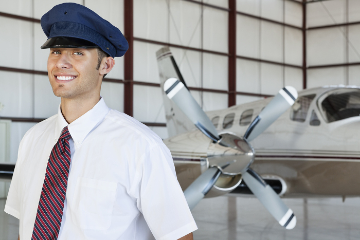 pilot Portrait of handsome young pilot standing in front of airplane