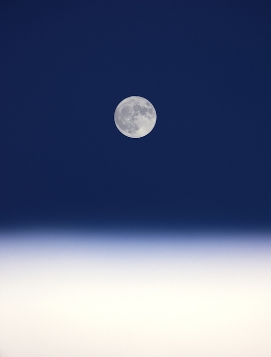 Full Moon Full Moon, seen in the night sky above clouds. The Moon is an airless, barren world, orbiting around 385,000 kilometres from the Earth. The dark areas are the lunar maria, plains of dark basaltic rock formed by ancient volcanic eruptions.