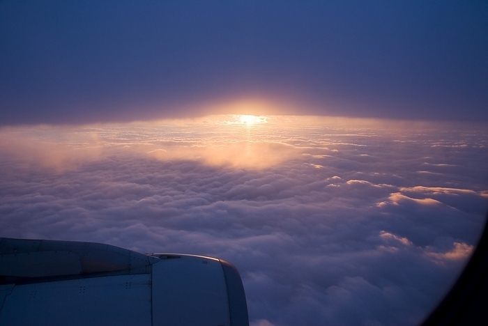 Sunset from aircraft Sunset from aircraft over Europe. The sun is about to appear from behind a high level cloud  nimbostratus  as it descends towards a lower level bank of cumulus cloud.