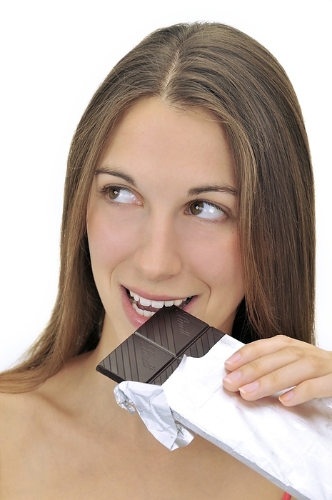 Woman eating dark chocolate Woman eating dark chocolate, wrapped in a foil wrapper. Chocolate is a sweet snack food prepared from the beans of the cocoa plant  Theobroma cacao . Dark chocolate has a high cocoa content and little or no milk.