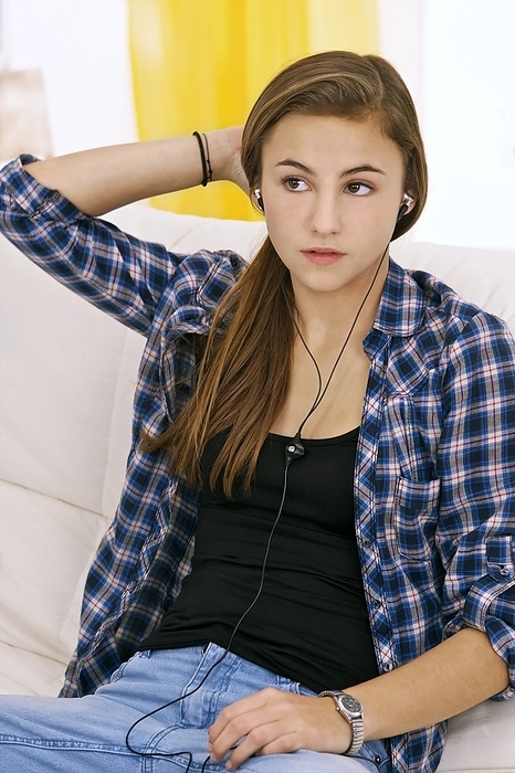 Teenager listening to music Teenager listening to music. Teenage girl listening to music through earphones attached to a portable media player.