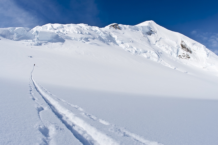 Skier skinning a trail to seracs and icefall at the head of Trimble Glacier below Mount Gerdine, Tordrillo Mountains, Alaska Range, Winter in Southcentral Alaska